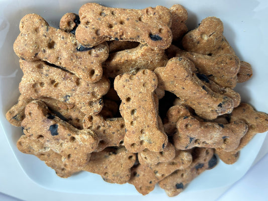 Dog bone-shaped biscuits made with peanut butter and blueberries on a white plate.