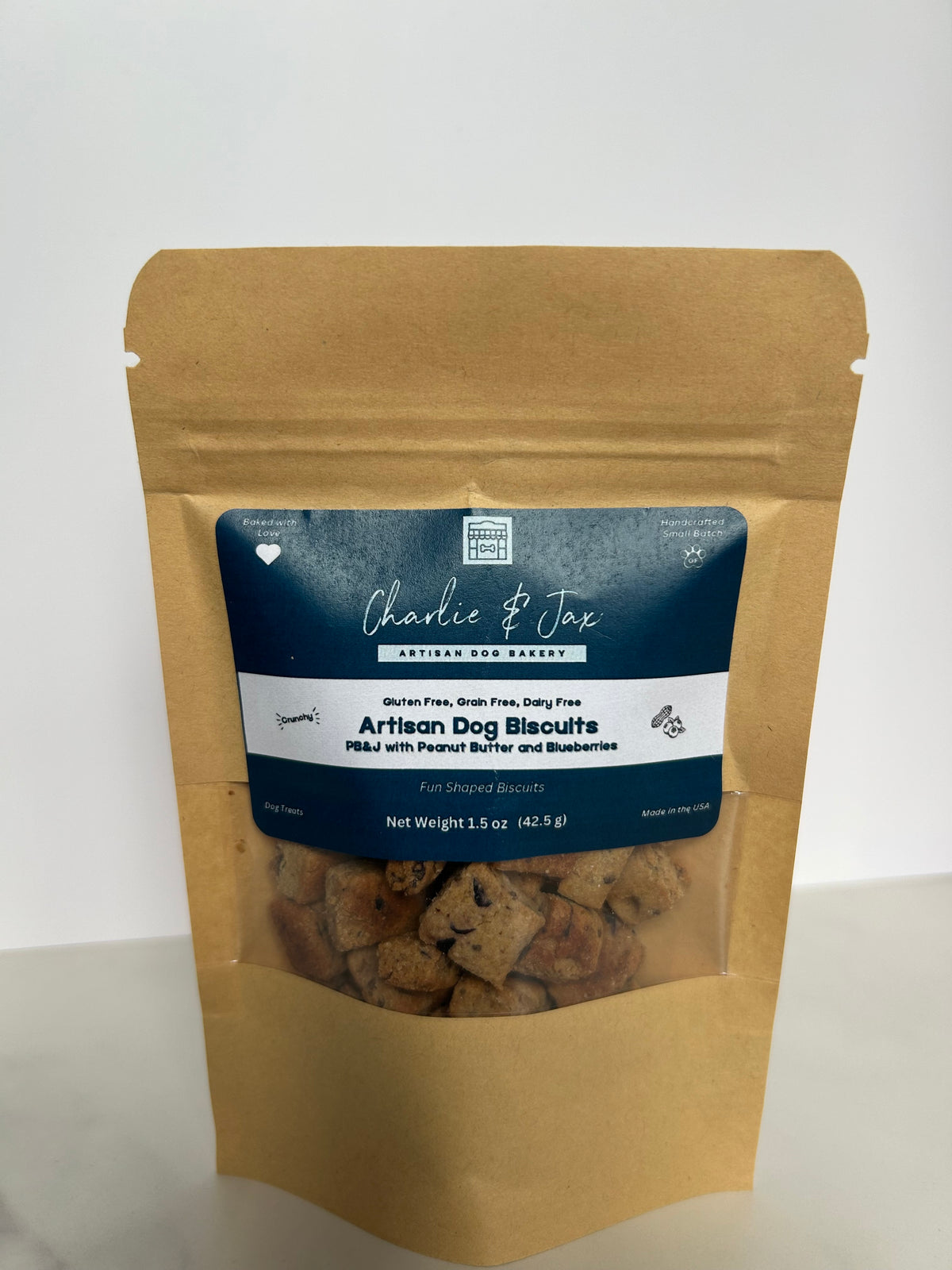 Charlie & Jax Artisan dog biscuits with Peanut Butter and Blueberry in a small pouch with a clear window showing the biscuits inside.