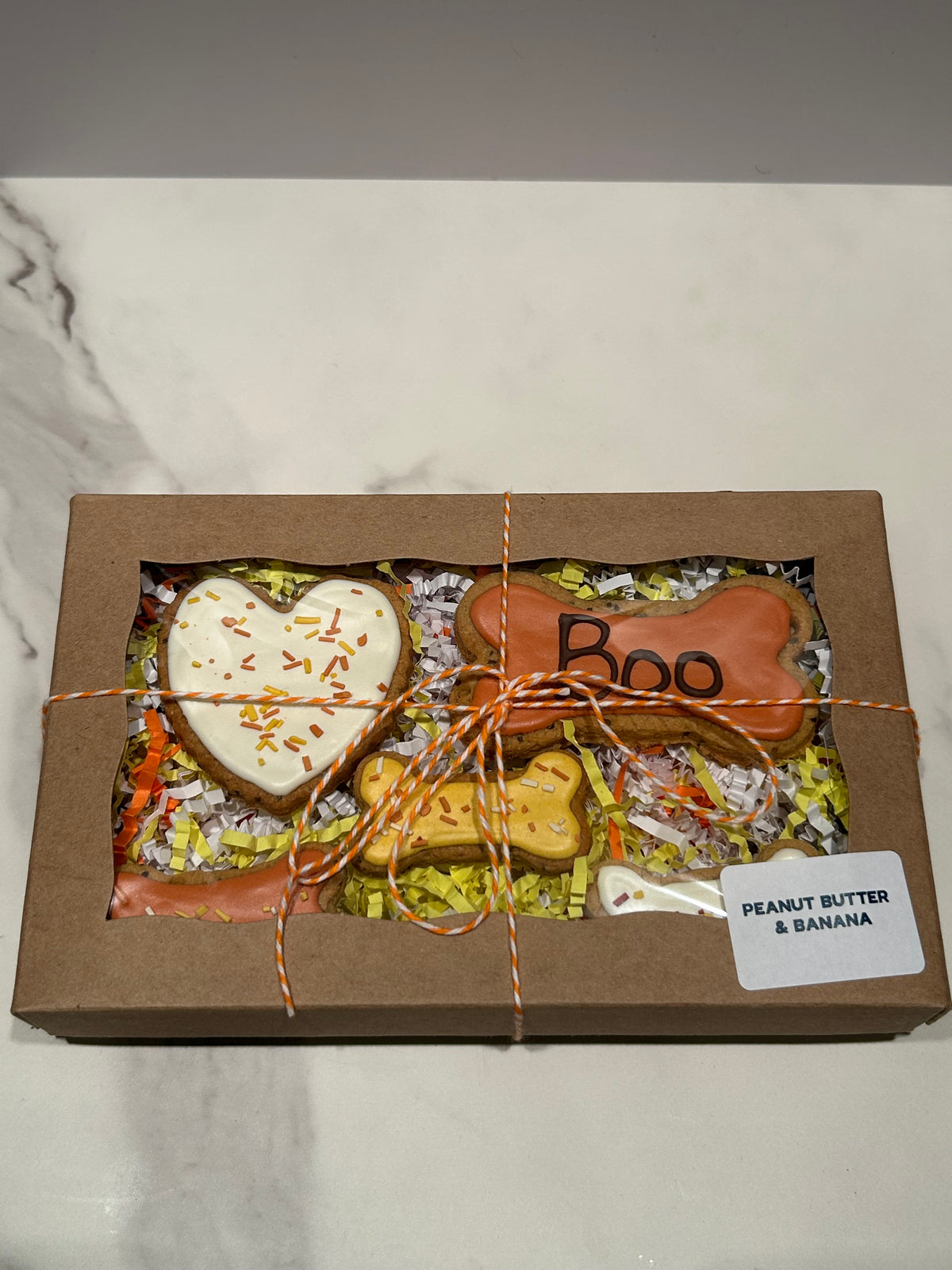 Box of halloween themed dog treats on a marble surface